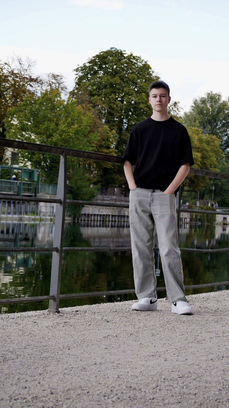 Tobi with his hands in his pockets at the same railing by the river