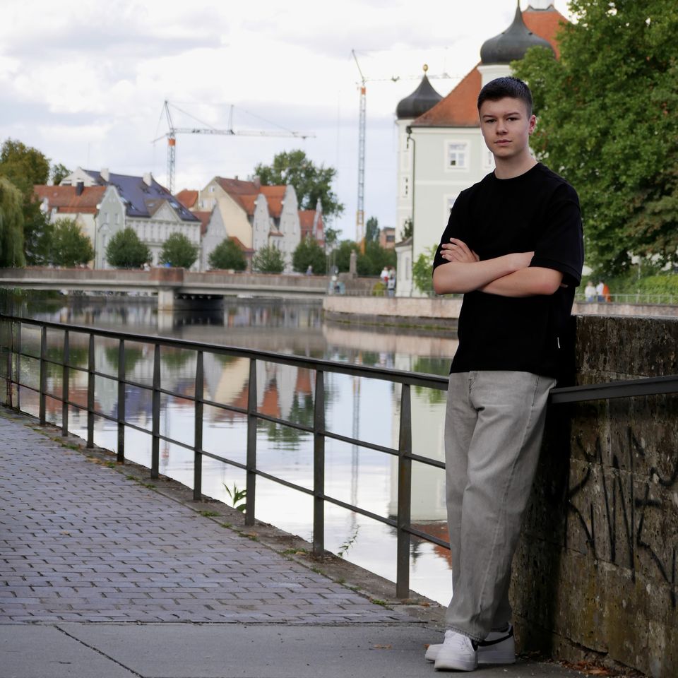 Tobi leaning on a wall by the river, the old town and a church with onion domes behind him